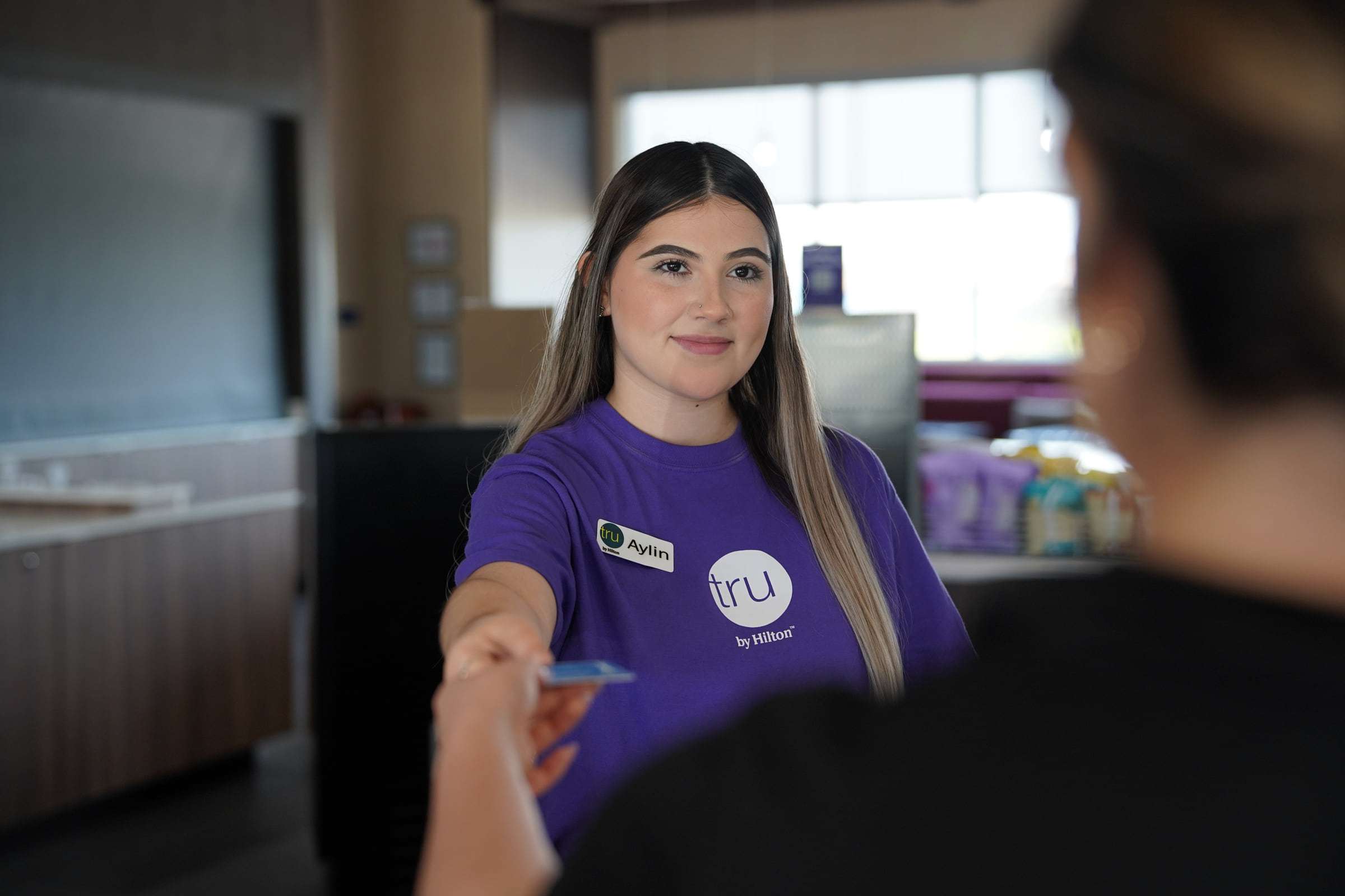 Tru by Hilton team member handing a key card to a guest