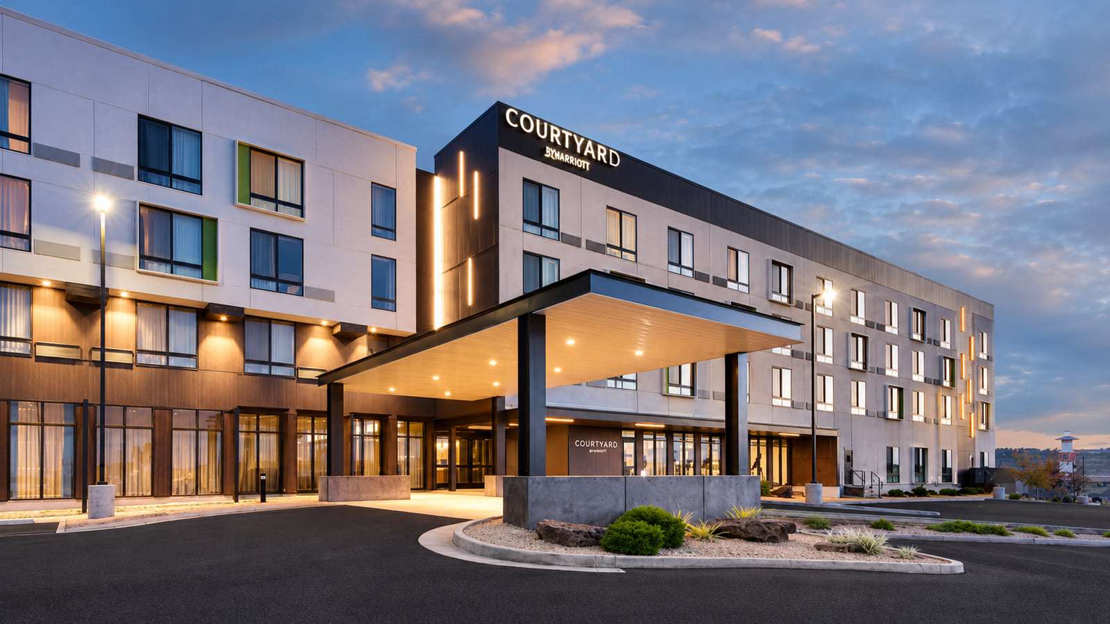 Courtyard by Marriott hotel at dusk with a white and charcoal facade and a lit entrance canopy