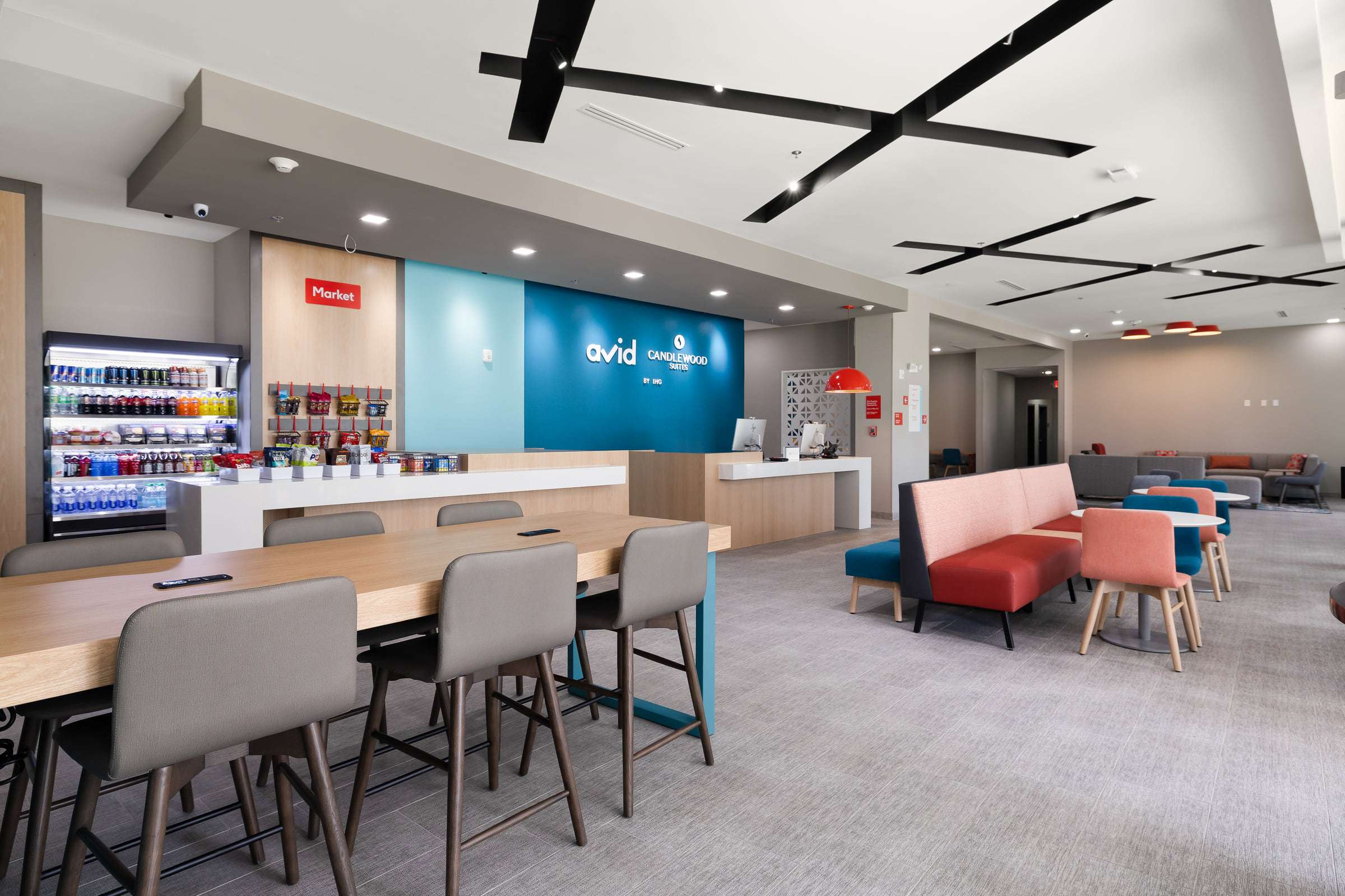 Shared avid and Candlewood Suites lobby with front desk, snack market, communal table and lounge seating