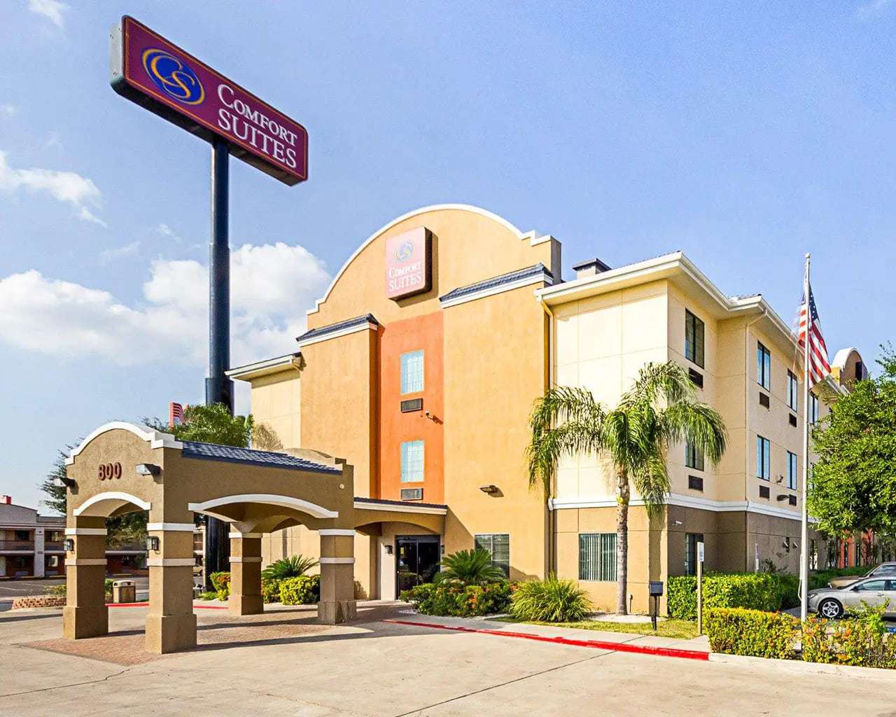 Comfort Suites exterior with tall pylon sign, porte cochere, palm tree and US flag