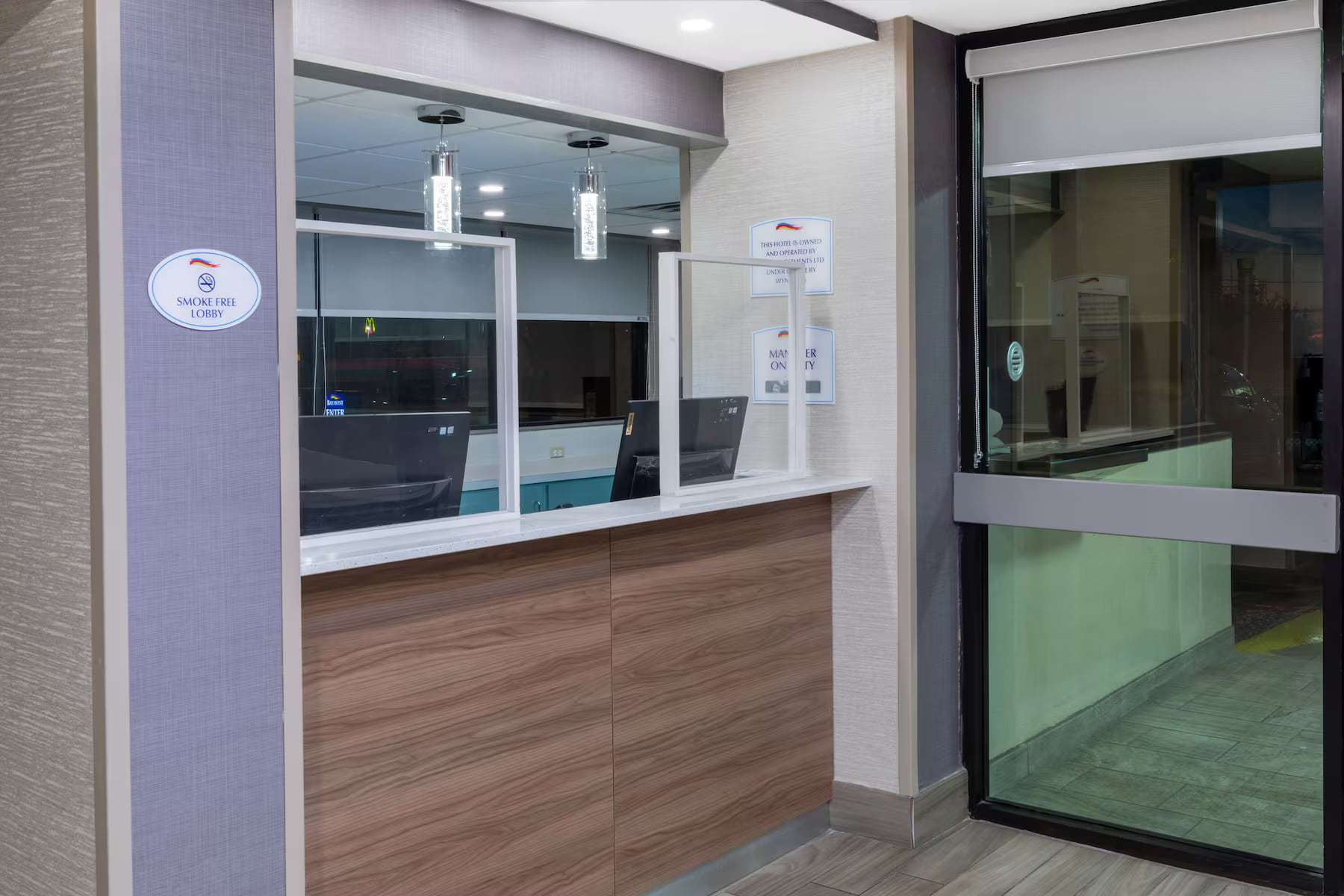 Lobby front desk with wood-panel counter next to the glass entrance doors