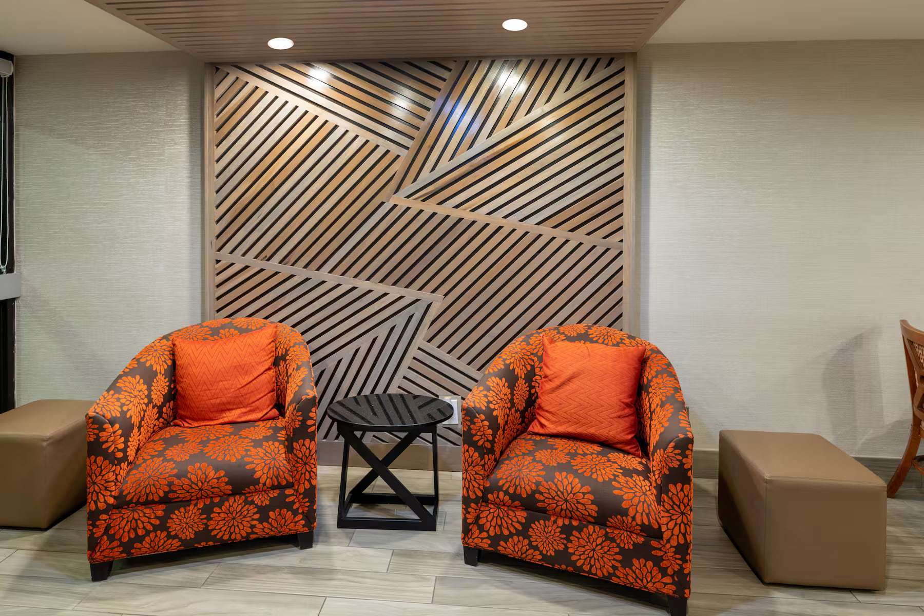 Lobby seating with two orange armchairs in front of a slatted wood accent wall