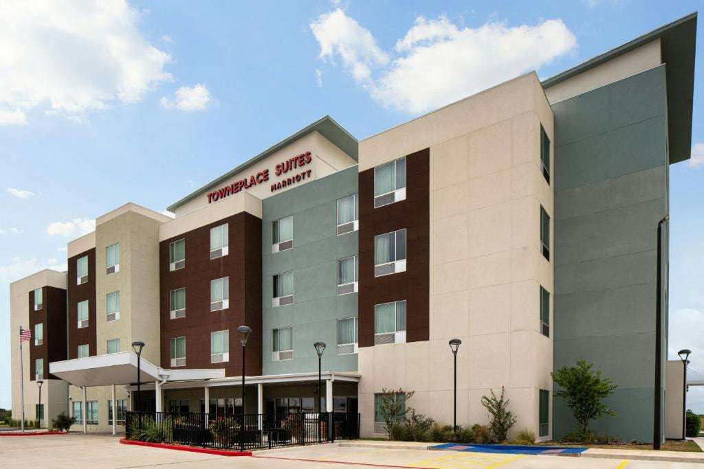 Four-story TownePlace Suites facade with covered entrance and landscaping on a sunny day