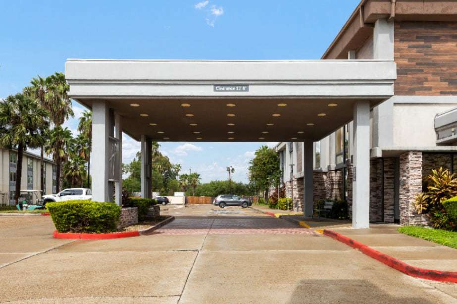Drive-through porte-cochere with clearance sign, palm trees and the hotel wings on both sides