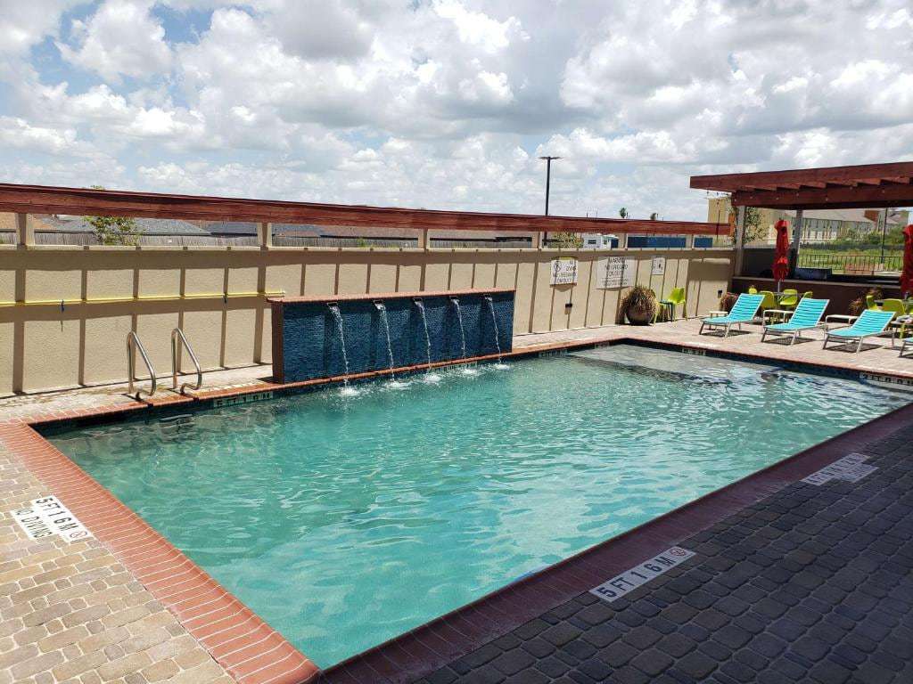 Outdoor pool with waterfall wall, turquoise lounge chairs and shaded pergola patio