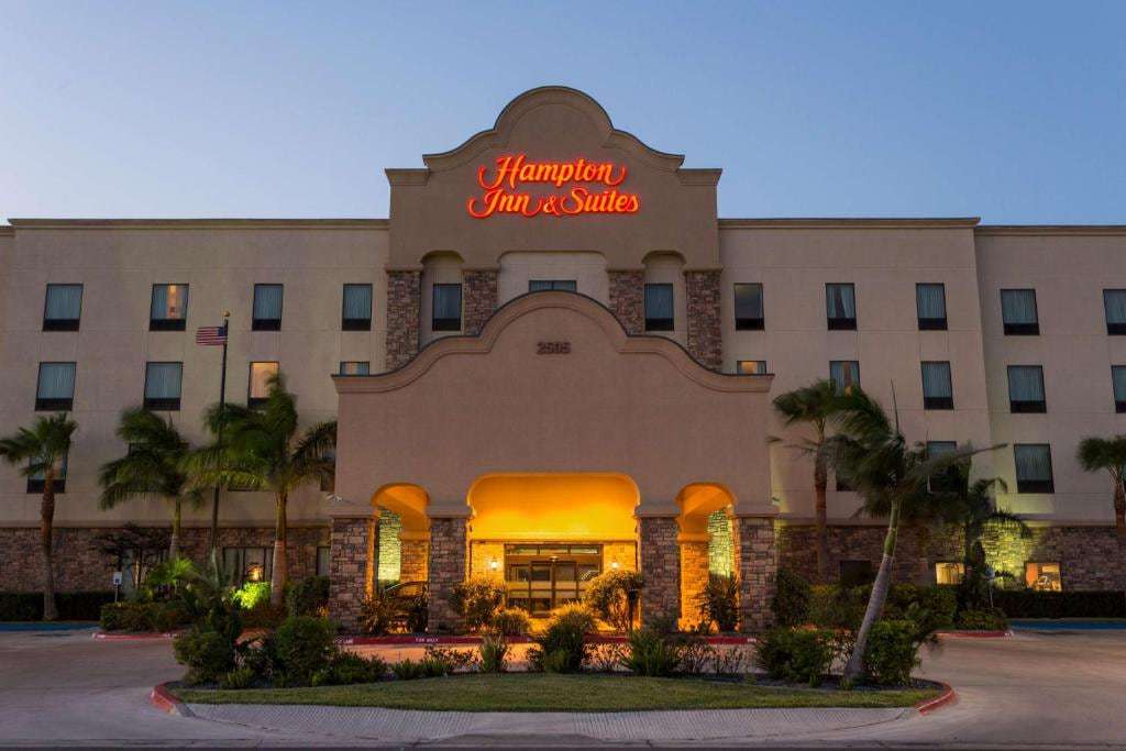 Front facade at dusk with illuminated Hampton Inn & Suites sign, arched entrance and palm trees