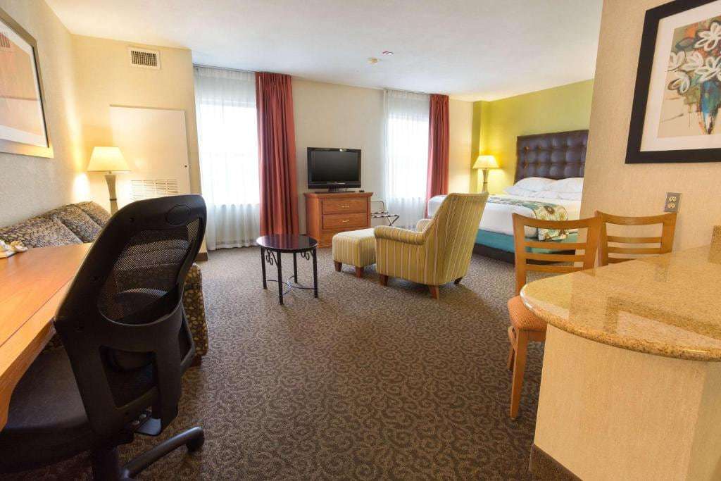 Studio suite with king bed, armchair and ottoman, sofa, work desk, flat-screen TV and kitchenette bar