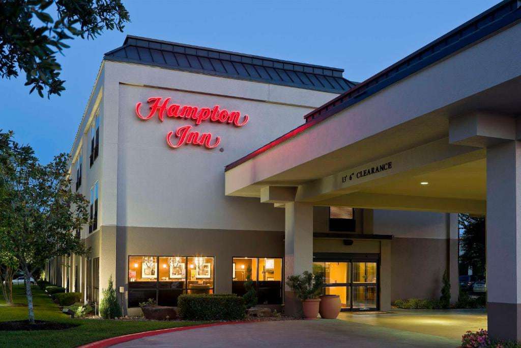 Lit Hampton Inn sign above the covered front entrance and lobby windows at dusk