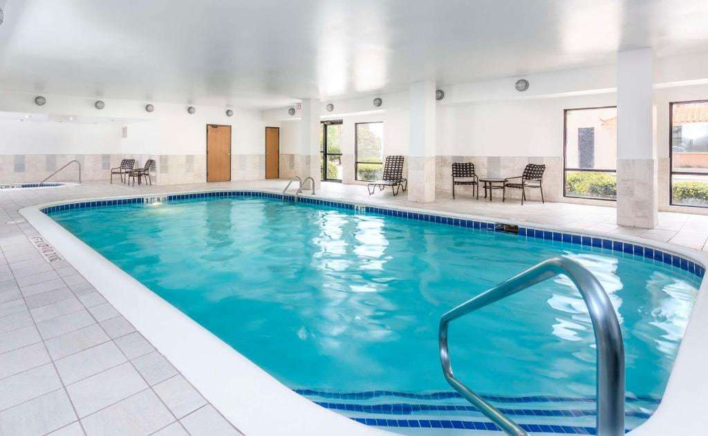 Indoor pool with tiled deck, lounge chairs and tall windows