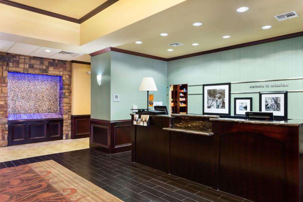 Lobby front desk with a Welcome to Mission wall sign, framed photos and a lit stone wall feature