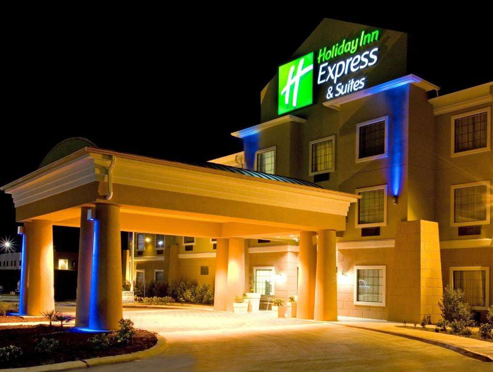 Hotel entrance and porte-cochere lit up at night beneath the illuminated Holiday Inn Express & Suites sign