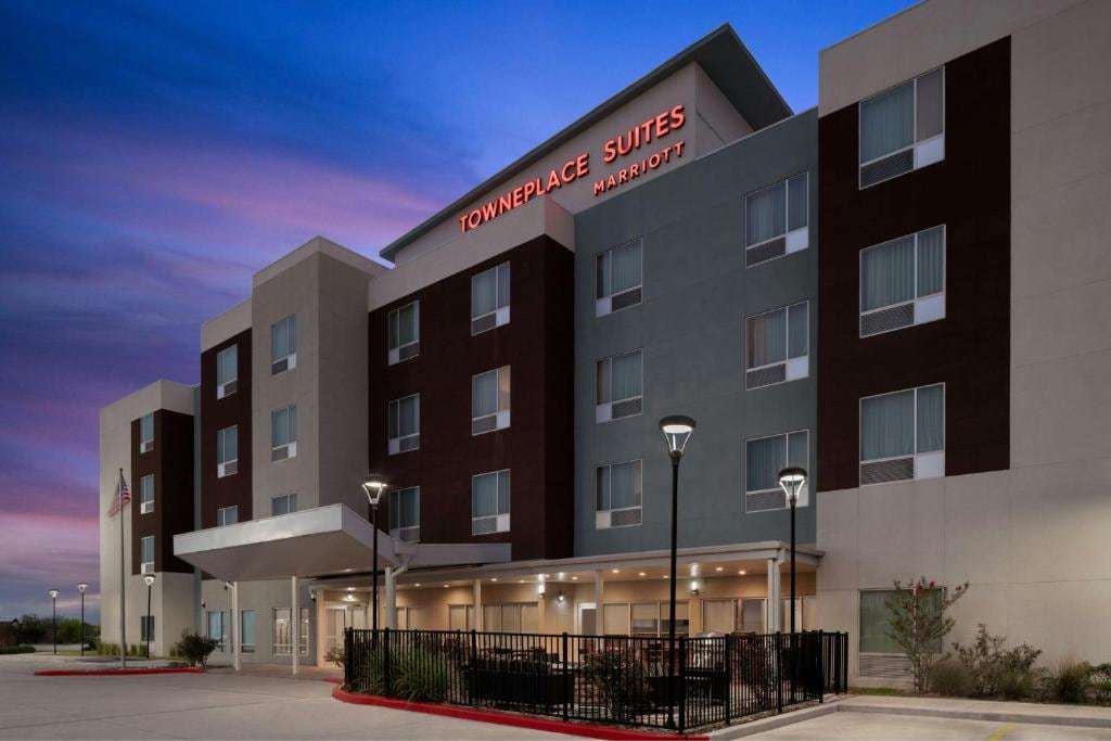 TownePlace Suites Kingsville at dusk with illuminated sign and fenced front patio