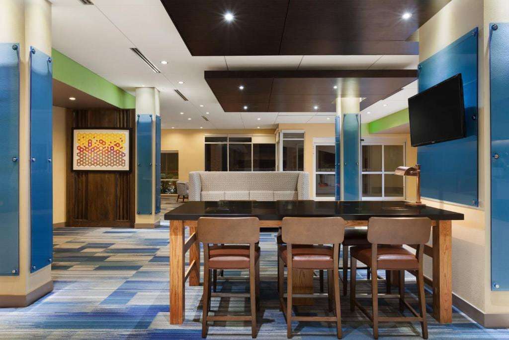 Lobby communal high-top table with wood stools, wall-mounted TV and blue glass column wraps
