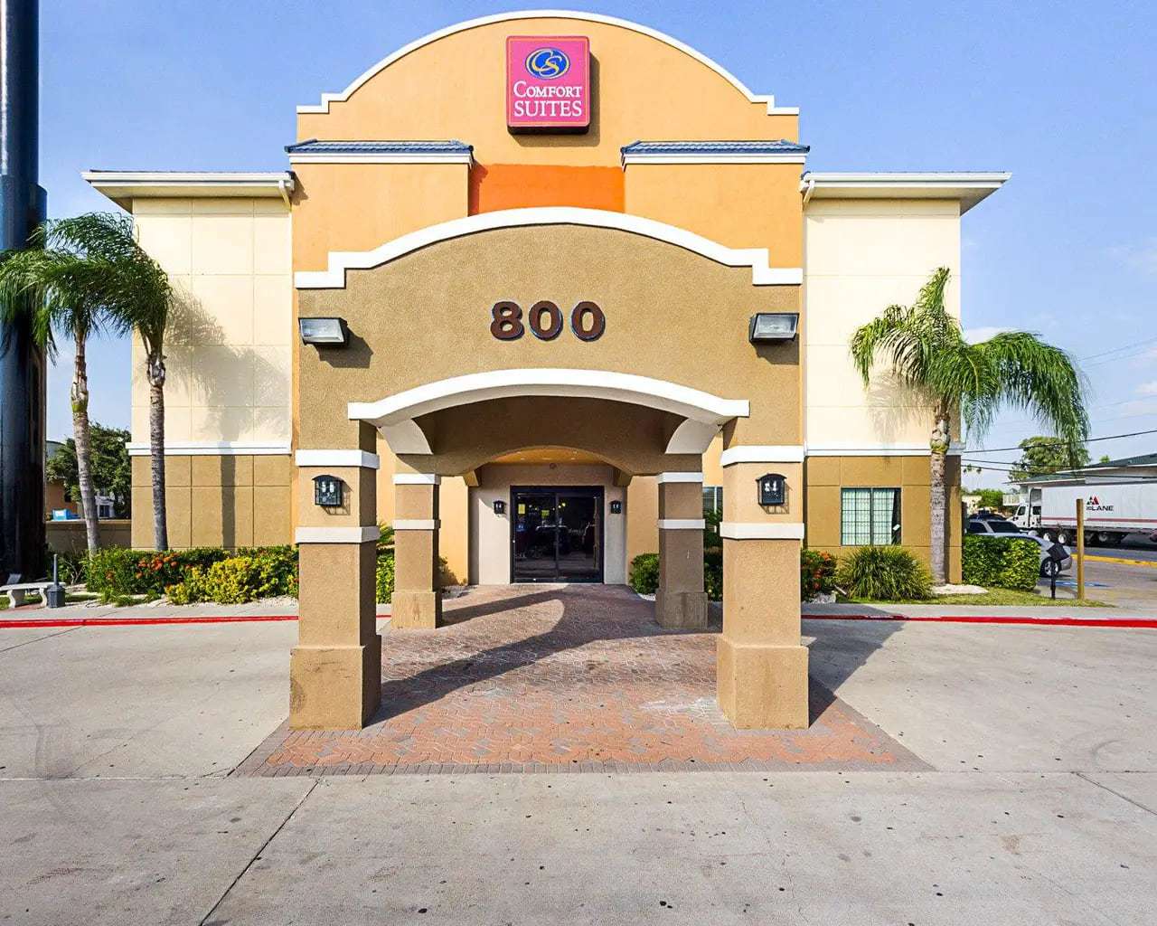 Front entrance with 800 address arch, covered drop-off, glass doors and palm trees
