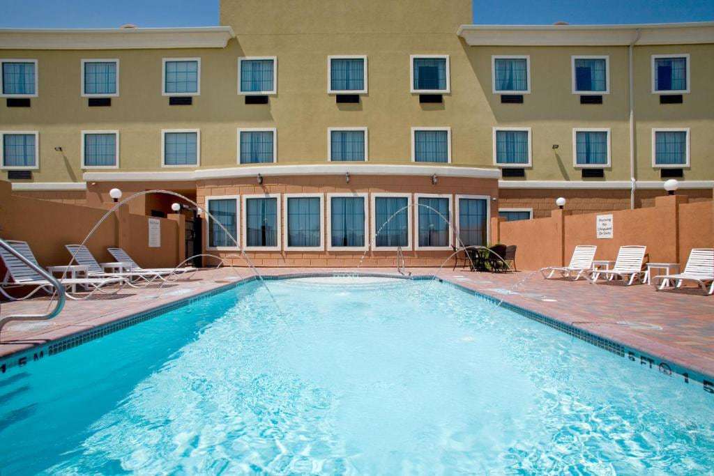 Outdoor pool with arching water jets, white lounge chairs and the hotel facade behind