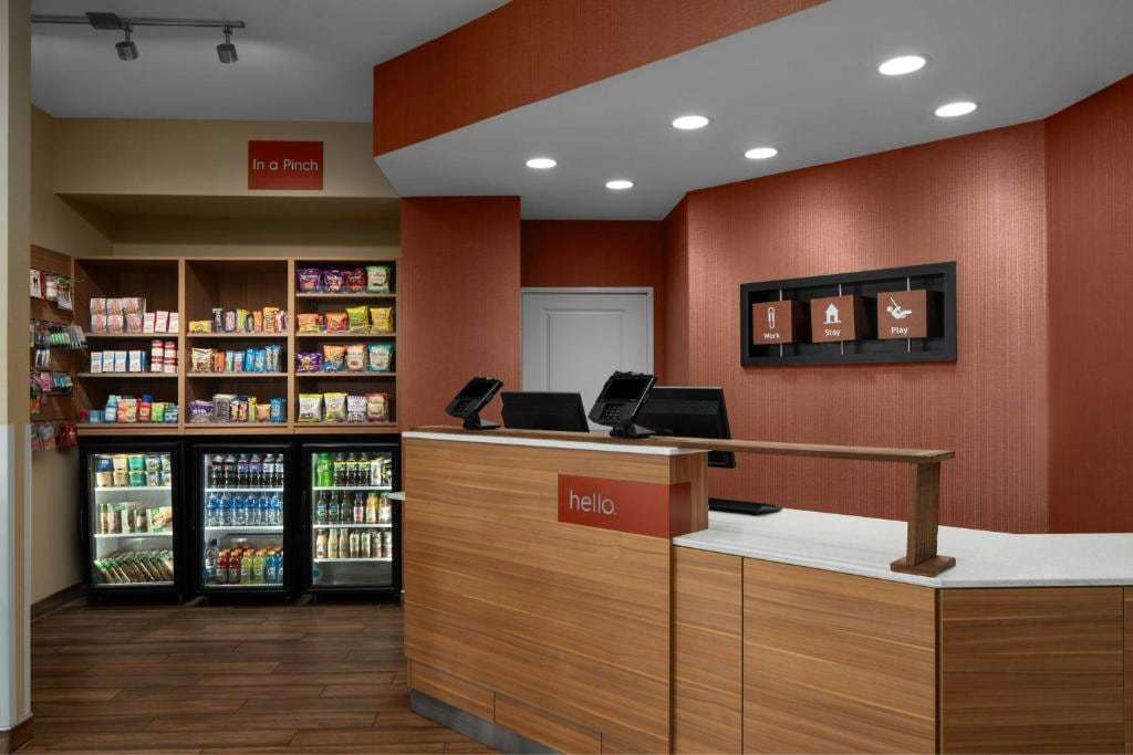Lobby front desk beside a grab-and-go market with snack shelves and drink coolers