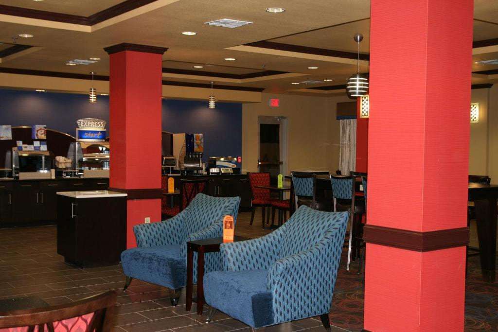 Lobby seating with blue armchairs between red columns, Express Start breakfast bar and dining tables behind
