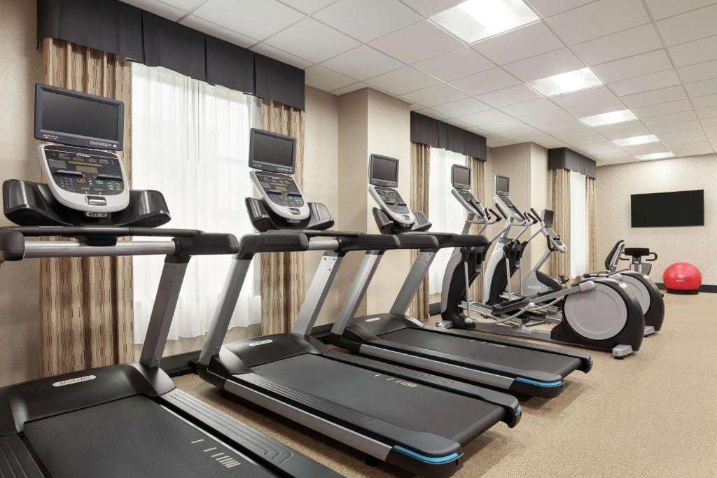 Fitness center with a row of treadmills, ellipticals and a wall-mounted TV