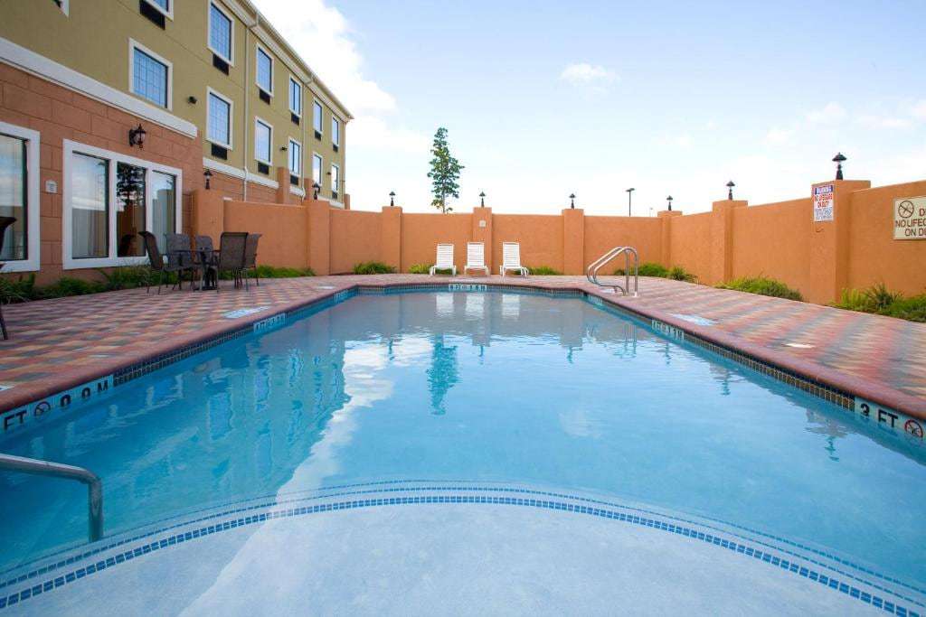 Outdoor pool with handrail and white lounge chairs inside a walled courtyard