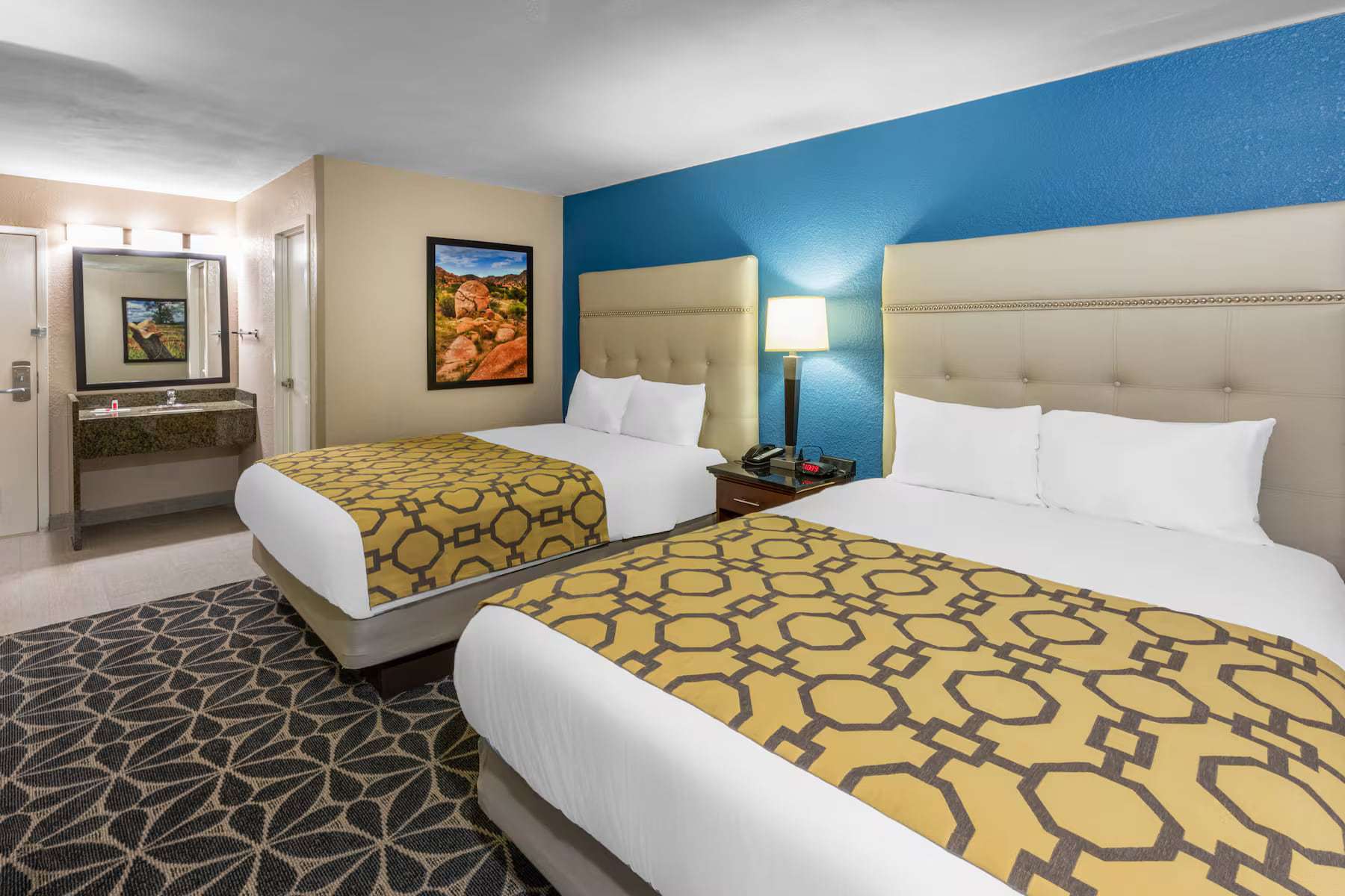 Room with two queen beds and a vanity area in the background