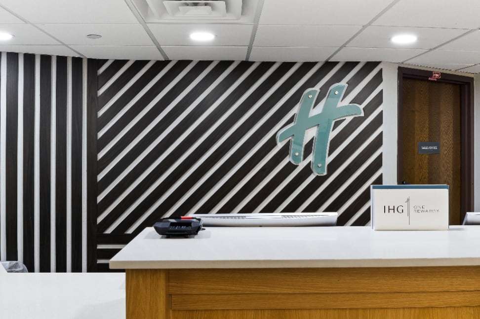 Front desk counter with the Holiday Inn H logo on a black-and-white striped wall
