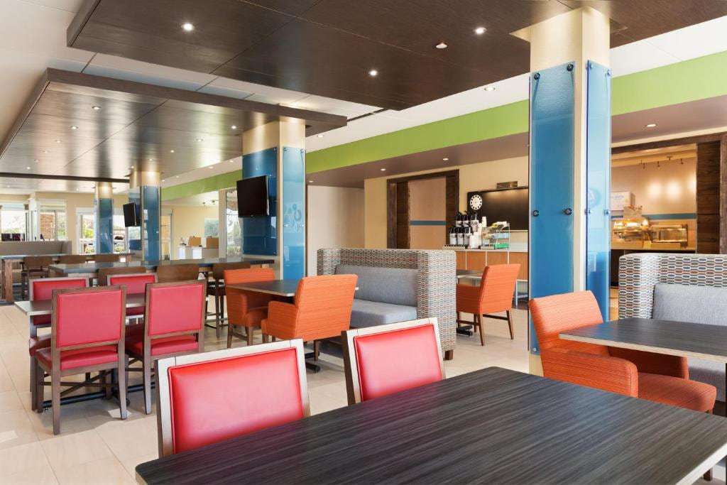 Breakfast dining area with red and orange chairs, booth seating and coffee station
