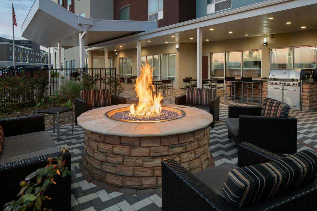 Outdoor patio with lit fire pit, wicker lounge chairs, bar seating and stainless steel grill