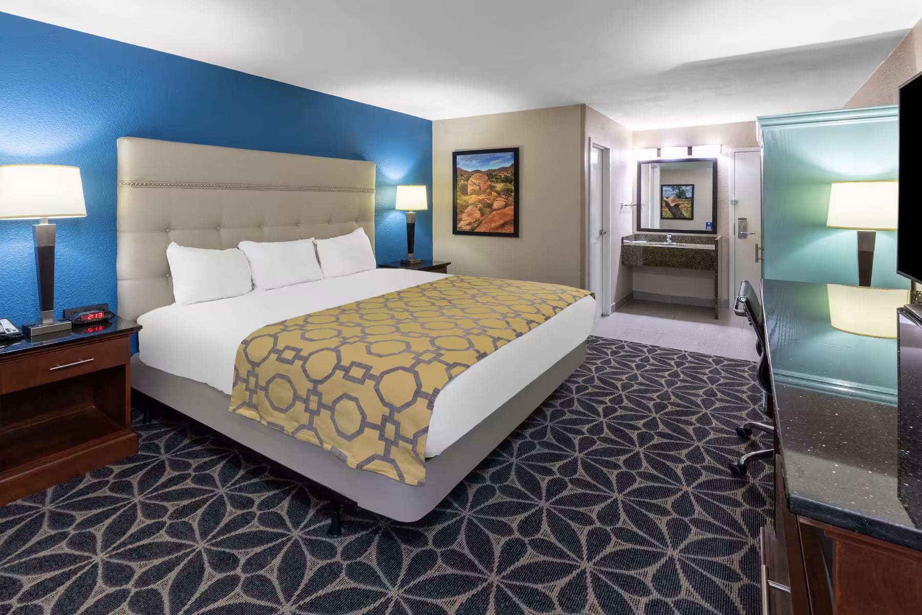 King room with tufted headboard, nightstands and separate vanity area