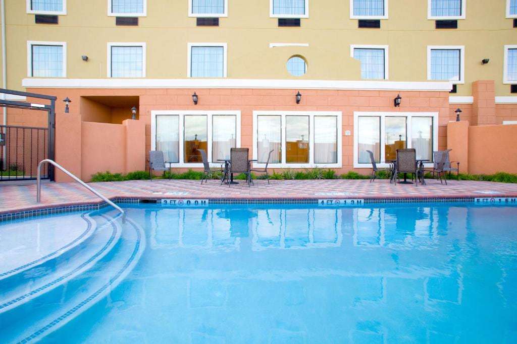 Outdoor pool with entry steps and patio tables beside the hotel's ground-floor windows