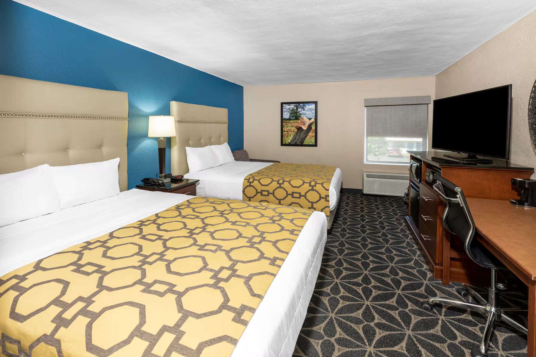 Two queen beds facing a work desk and flat-screen TV