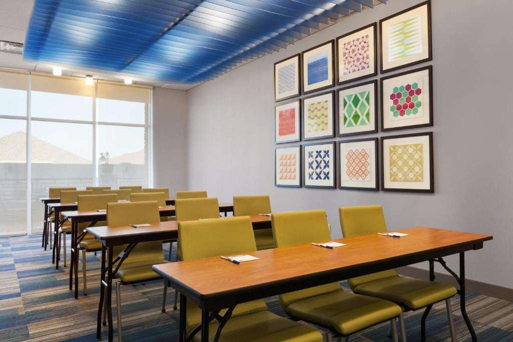Meeting room set classroom-style with green chairs, wood tables and framed geometric art