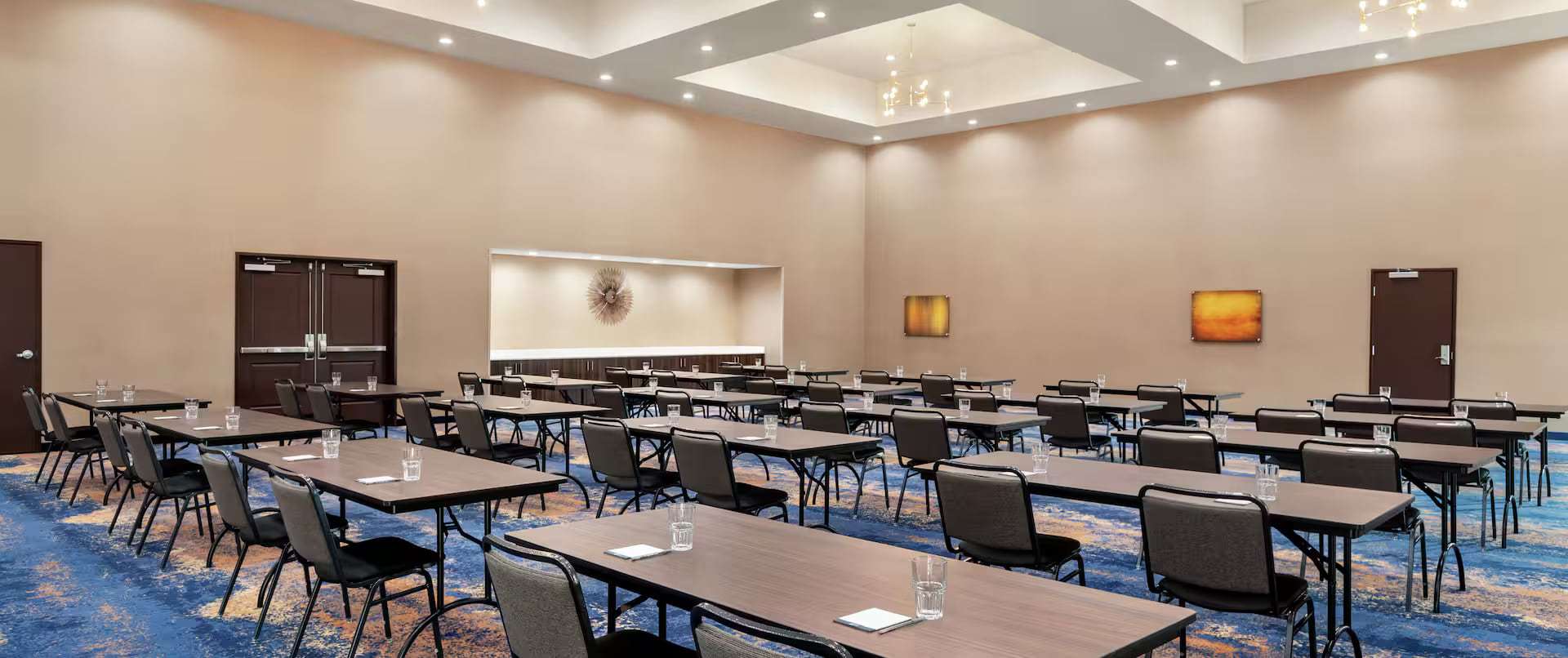Meeting room set classroom style with rows of tables, chairs and water glasses