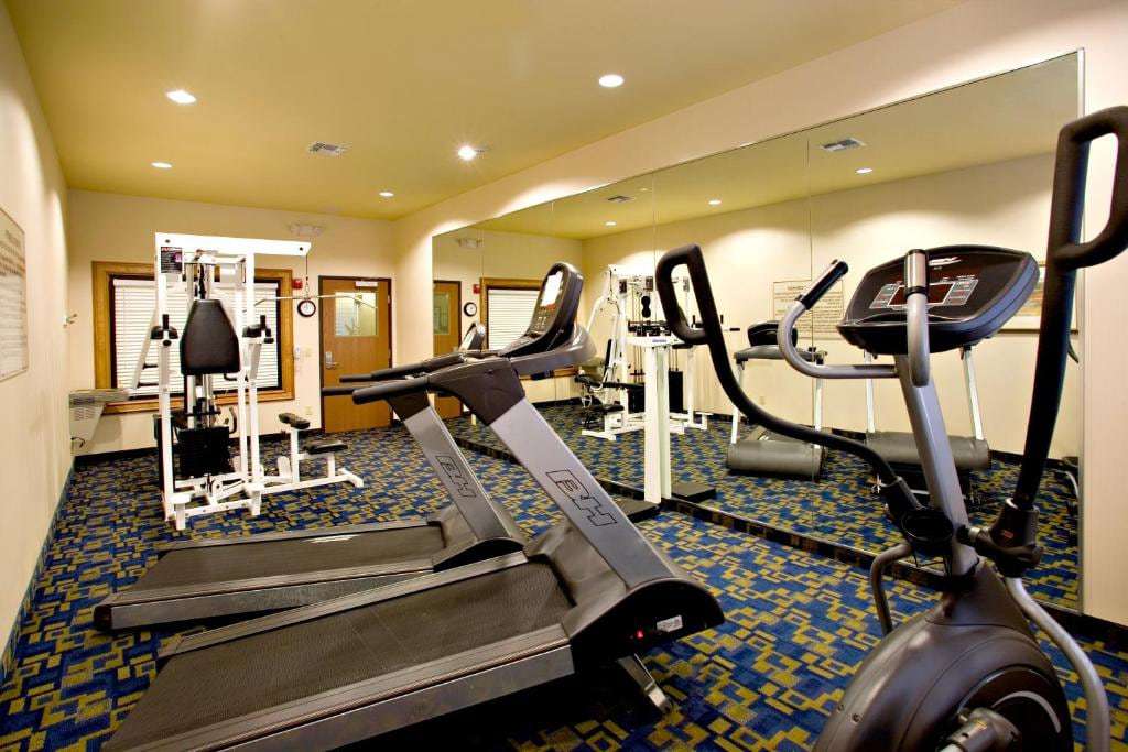 Fitness center with treadmills, elliptical, weight machine and a mirrored wall