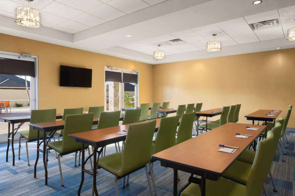 Meeting room with classroom tables, green chairs, chandeliers, wall TV and patio doors