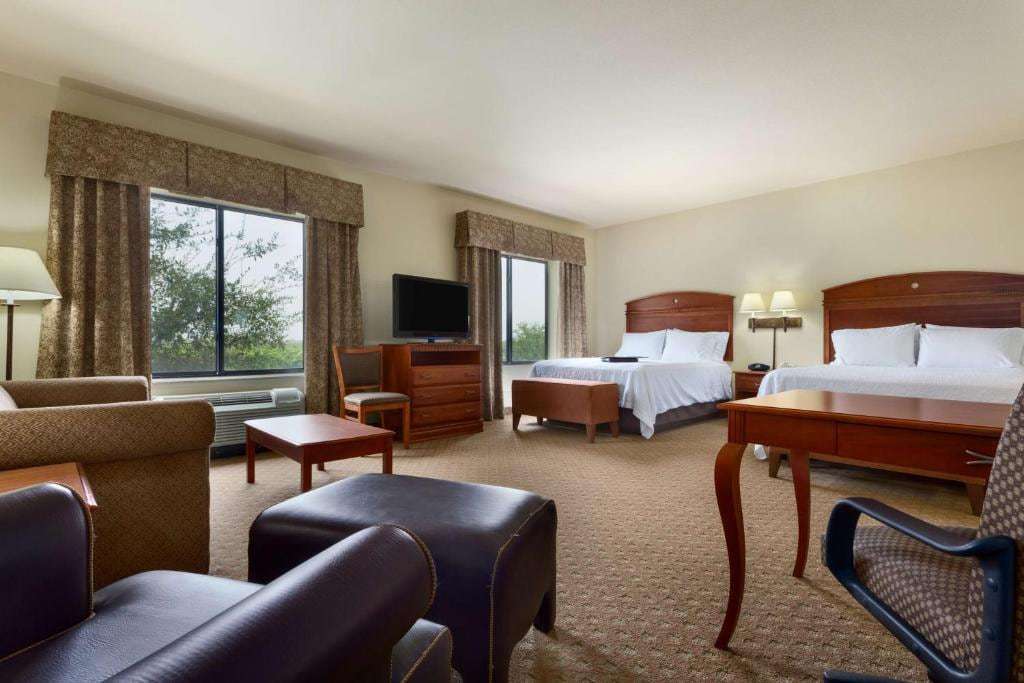 Studio suite with two queen beds, armchairs, ottoman, coffee table and work desk
