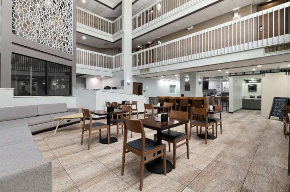 Atrium dining tables under white-railed balconies, with the breakfast area in the back