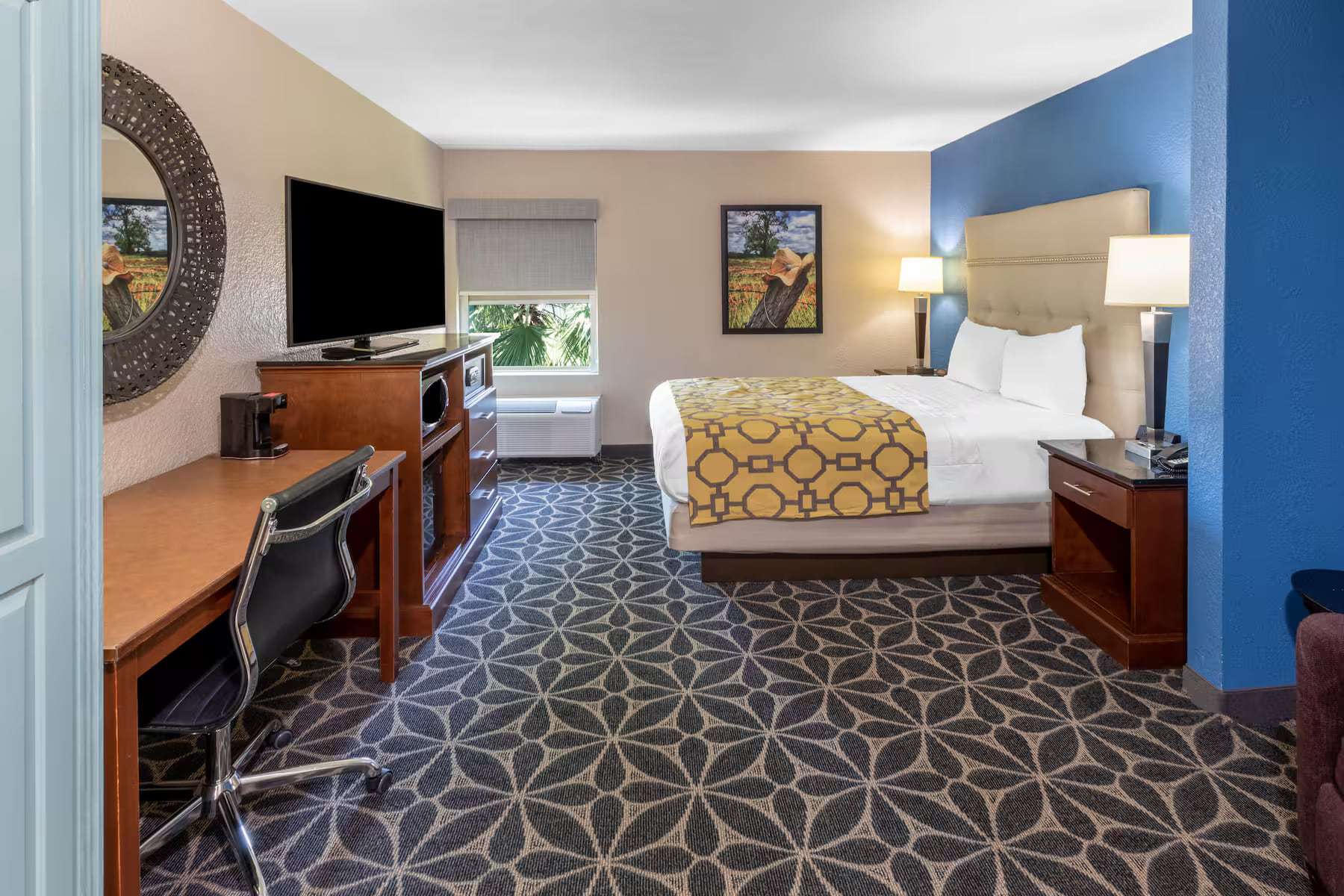 Room with one bed, work desk, flat-screen TV and microwave, seen from the doorway