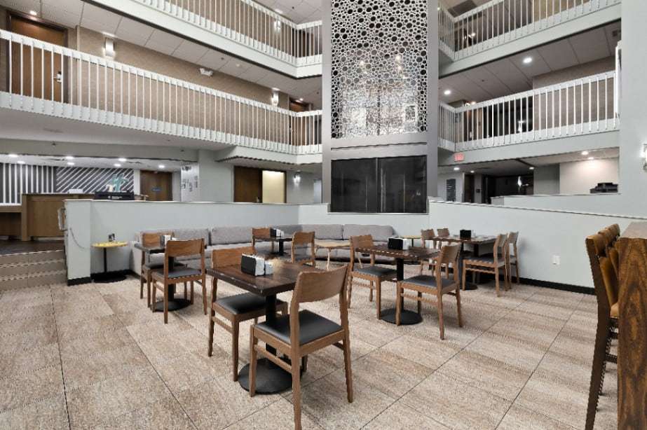 Atrium seating with wood dining tables, gray sectional sofa and a decorative screen wall