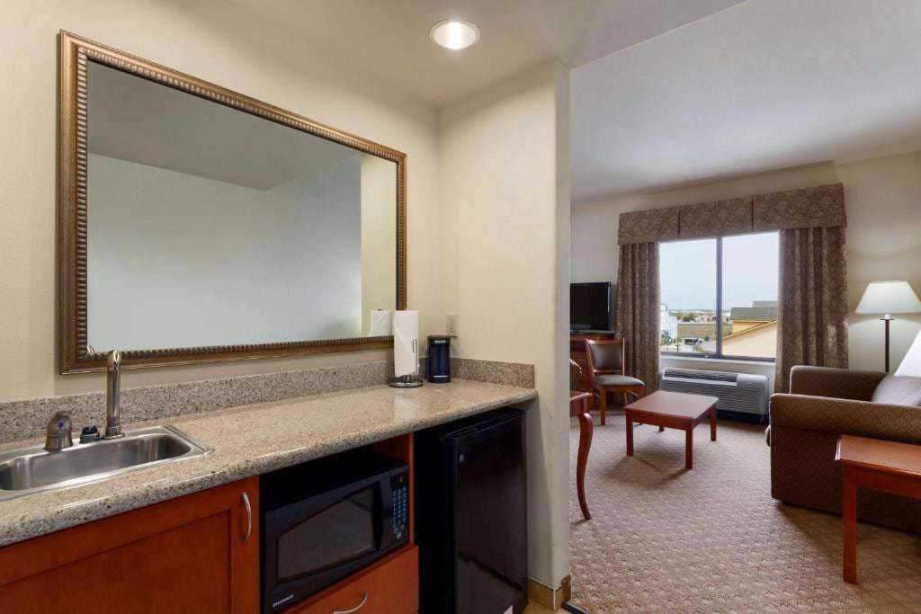 Suite wet bar with sink, microwave and mini-fridge next to a living area with sofa
