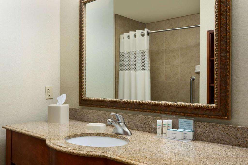 Bathroom vanity with granite counter, large framed mirror and toiletries
