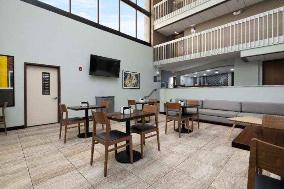 Lobby dining area with wood tables and chairs, wall TV and clerestory windows