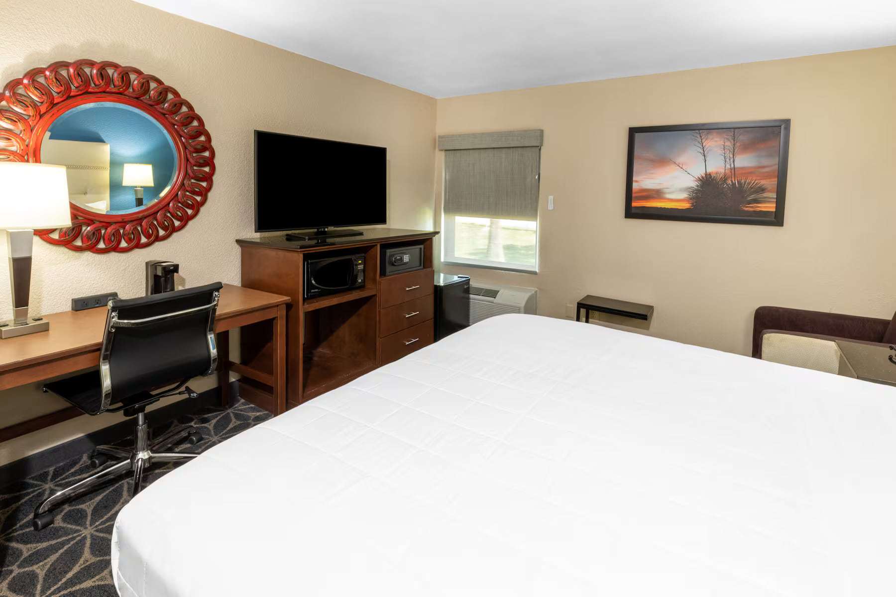 Room with a large bed, work desk, TV, microwave, mini fridge and in-room safe