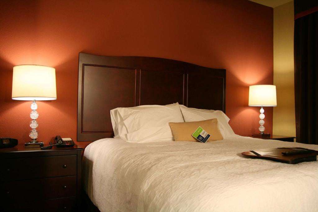 King bed with white linens between two nightstands with lit table lamps
