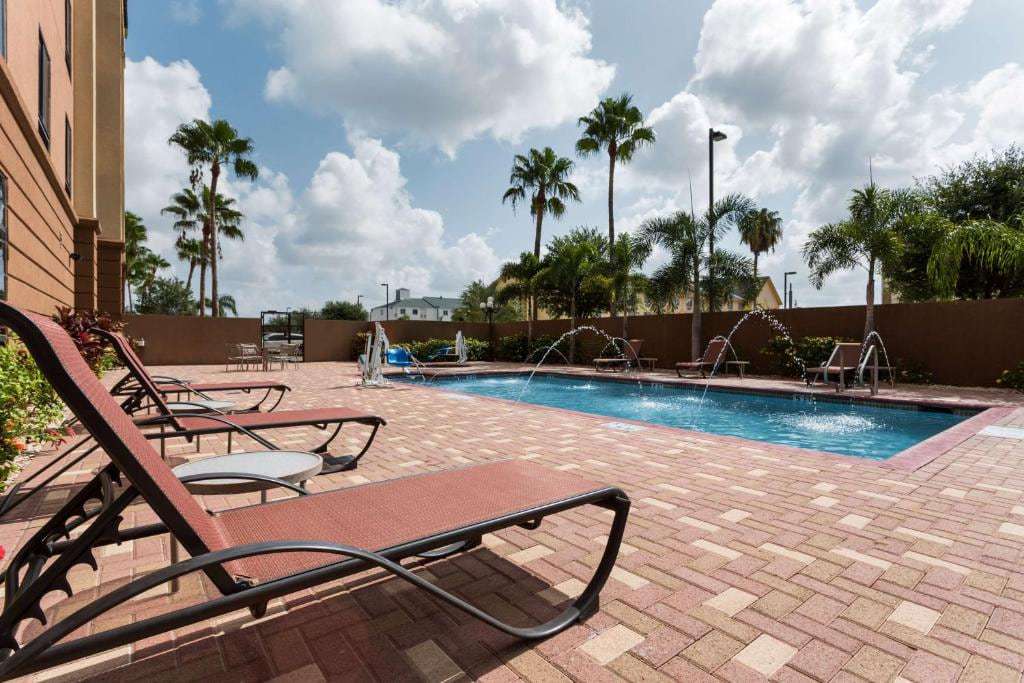 Outdoor pool with fountain jets, paver deck, lounge chairs and palm trees