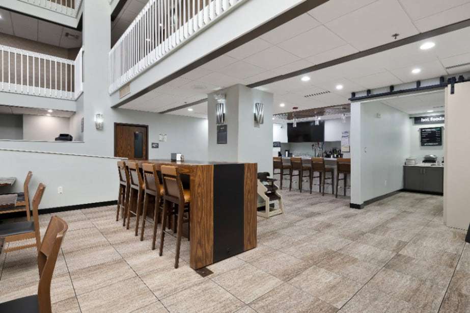 Communal high-top table with bar stools in the lobby, with the bar and buffet beyond