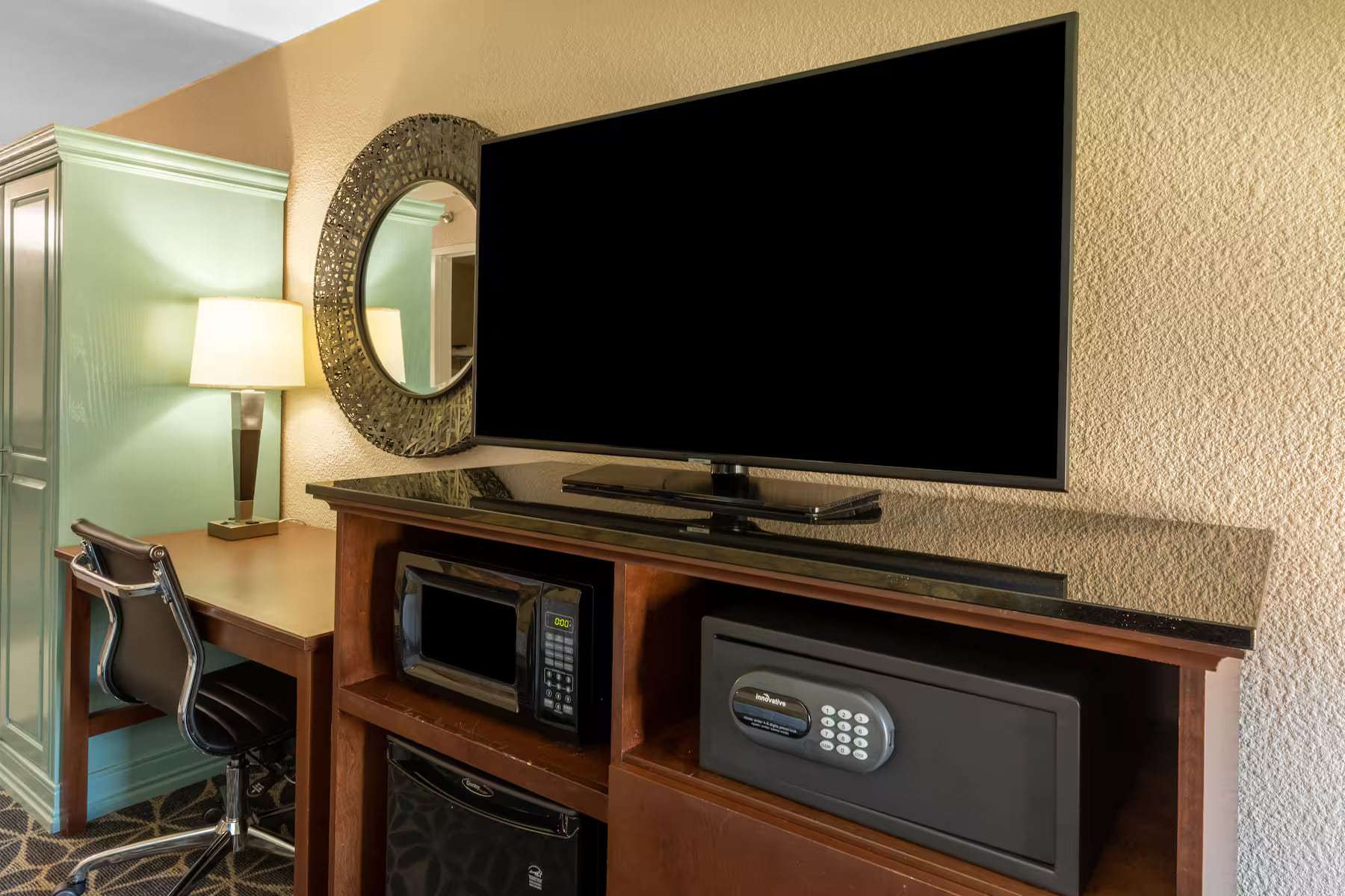 TV cabinet with microwave, mini fridge and in-room safe beside the work desk