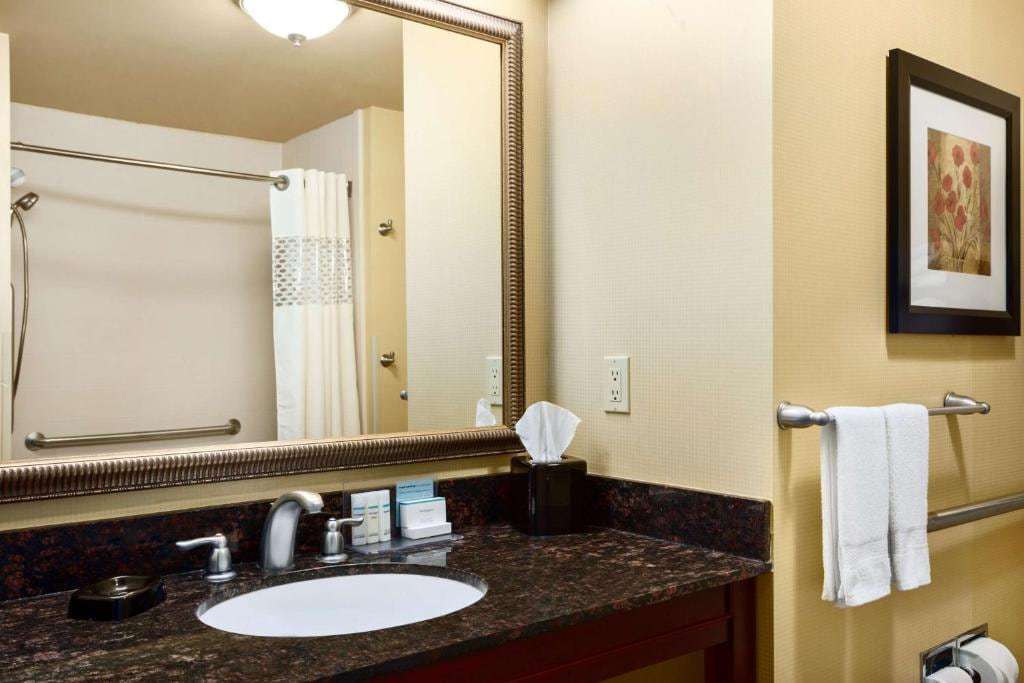 Bathroom with granite vanity, large mirror, grab bars and a shower with handheld showerhead