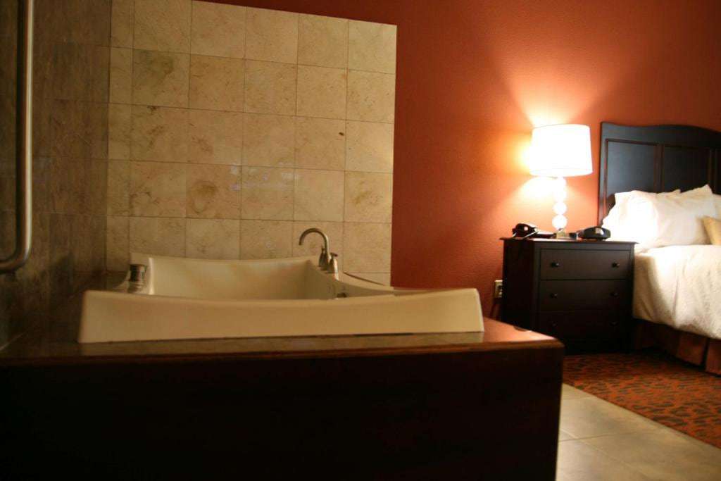 Built-in soaking tub with tiled backsplash beside the bed in a guest room