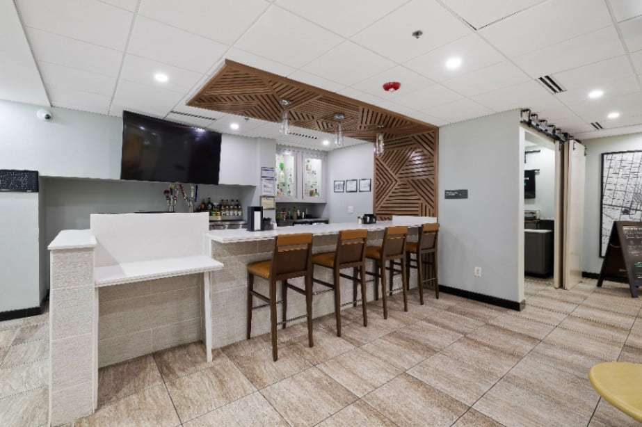 Lobby bar counter with stools under a wood slat ceiling feature