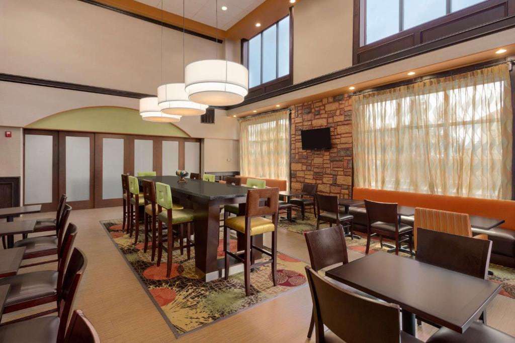 Breakfast dining area with communal high-top table, booth seating and stone accent wall